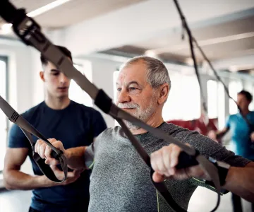 Older gentleman working out with supervision from a certified personal trainer