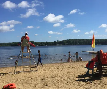 Kids swimming and sitting on the beach with lifeguard watching - Waterfront beach at Camp Yomechas