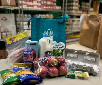 Table with a bunch of food like apples, milk, eggs, yogurt and more for the community market in Stoughton