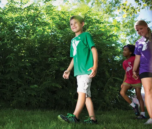 Boy walking threw the woods with some other campers and staff