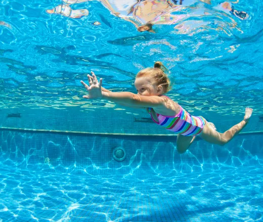 child learn swimming, diving in blue pool with fun - jumping deep down underwater with splashes. Healthy family lifestyle, kids water sports activity, swimming lesson with parents.