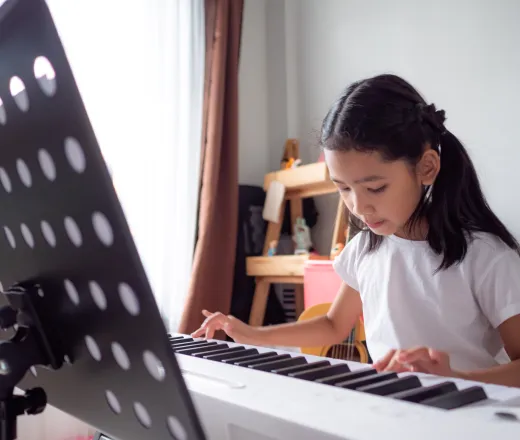 Asian little girl learning to play piano keyboard synthesizer with happiness