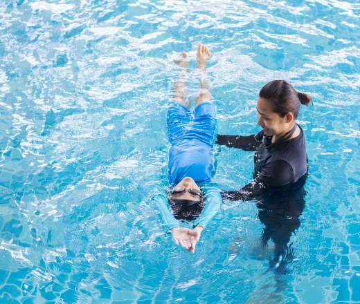 Girl learning to swim with swim instructor
