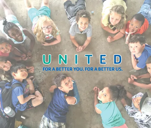 Group of kids laying down in a circle looking at the camera smiling