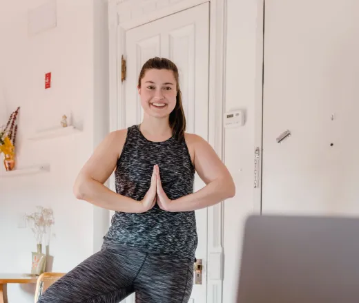 Woman standing in front of her computer doing a virtual yoga class