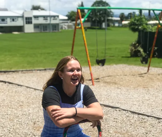 Smiling teenage girl sitting on a teeter totter outside on a playground